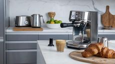 Breville Bambino Plus next to a latte and some croissants