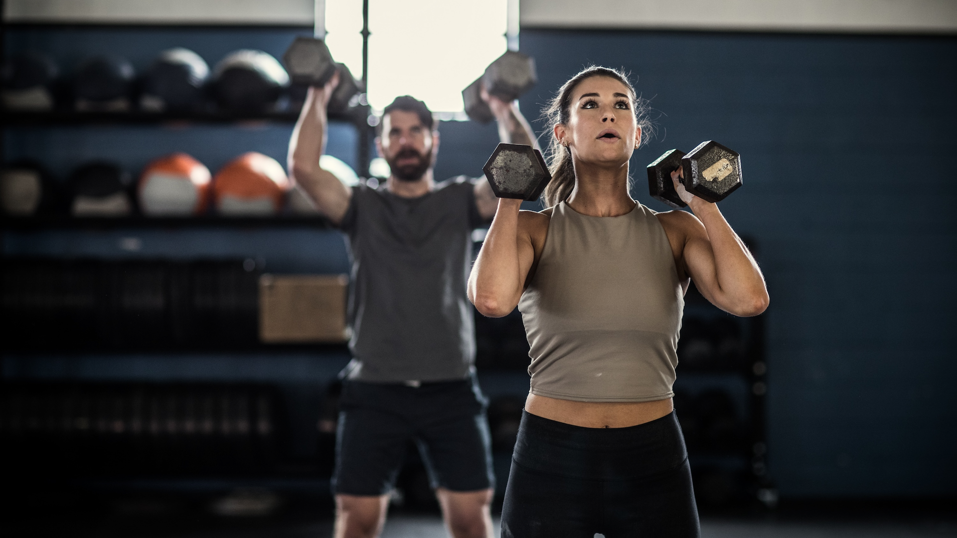 Woman lifting weights with a personal trainer