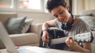 Young woman learning to play acoustic guitar