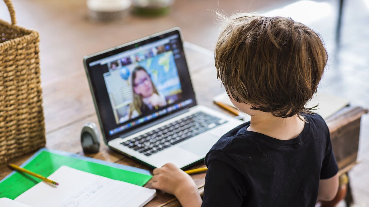 Young boy sat in front of laptop watching teacher