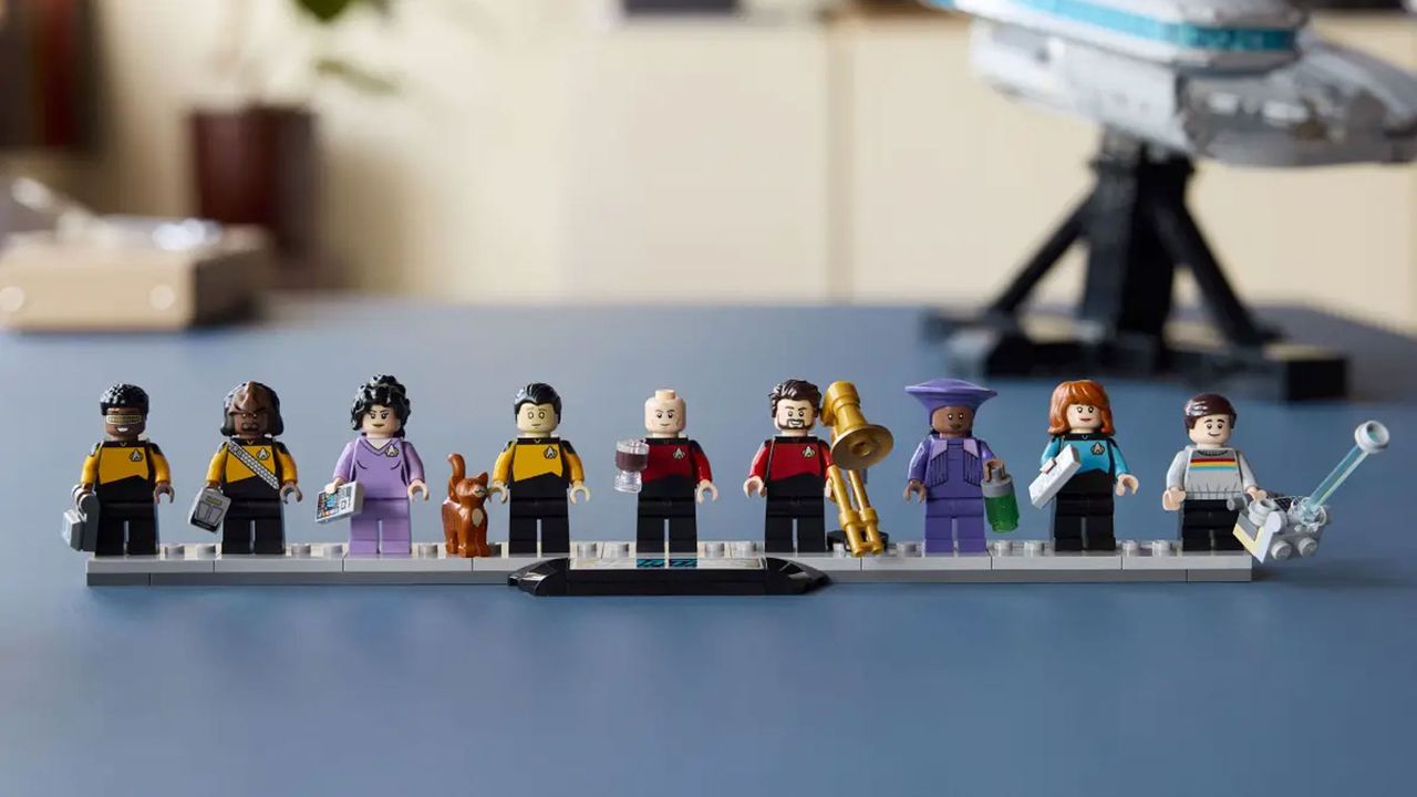 A grey brick-built spaceship is displayed with minifigures and an information plaque.