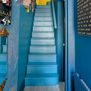 Hallway with stairs and walls painted a matching mid blue shade