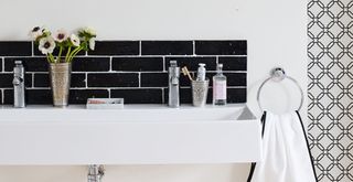 white bathroom with black metro tiled splashback behind a double ceramic sink to avoid a common bathroom design mistake