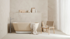 a neutral, beige bathroom with plaster-effect walls and a freestanding tub