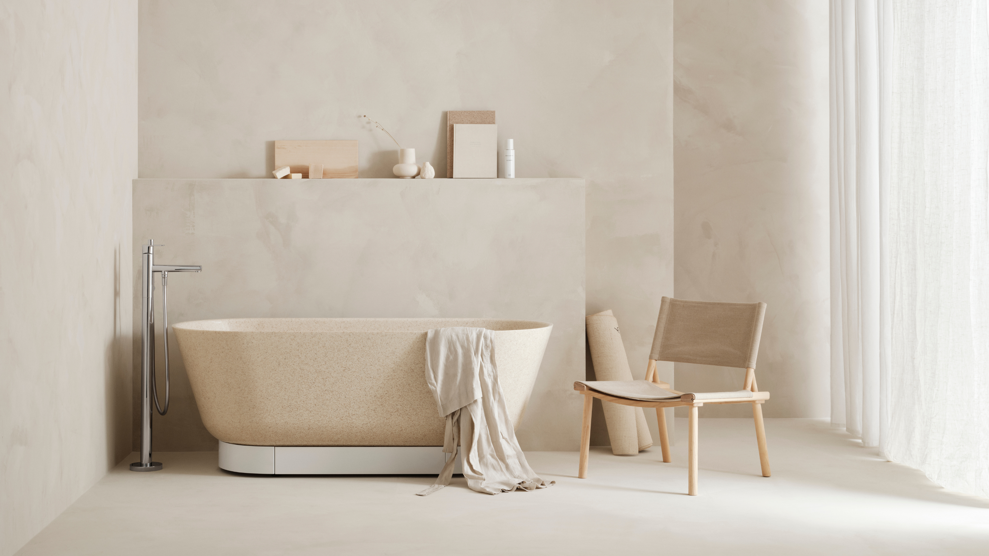 a neutral, beige bathroom with plaster-effect walls and a freestanding tub
