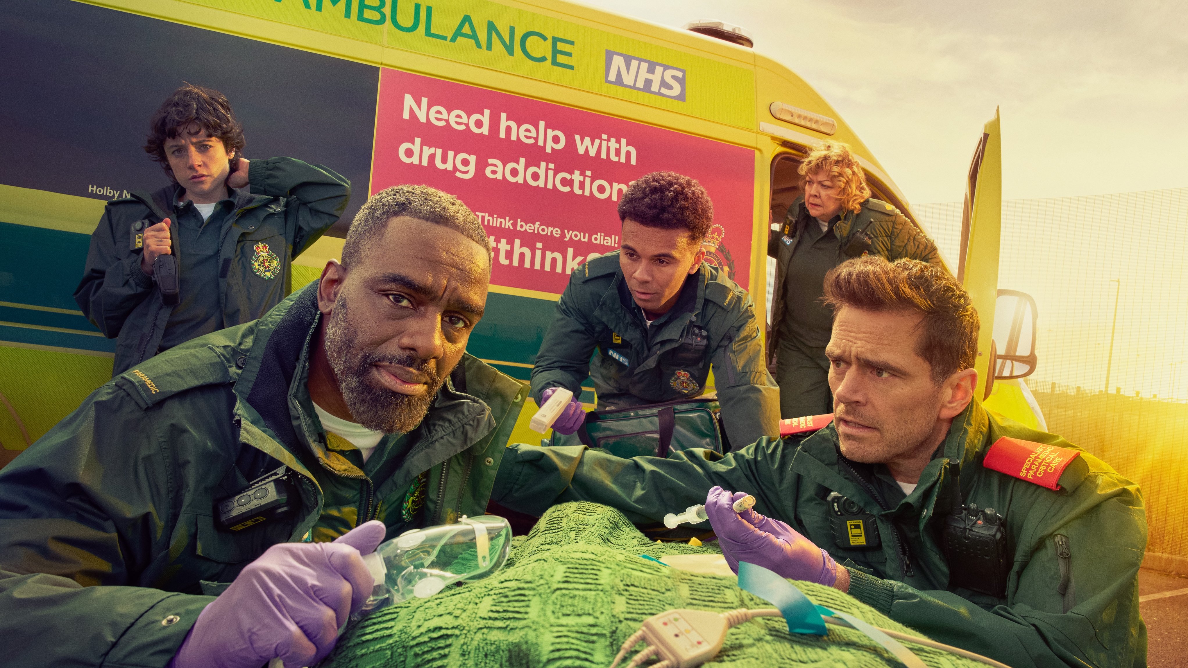 A press shot of Casualty cast standing in front of an ambulance for Supply and Demand