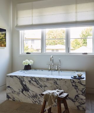 A black-and-white marble bathtub in front of a large window