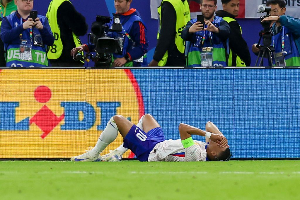 Kylian Mbappé of France lies injured on the grass during the UEFA EURO 2024 quarter-final match between Portugal and France at Volksparkstadion on July 5, 2024 in Hamburg, Germany.