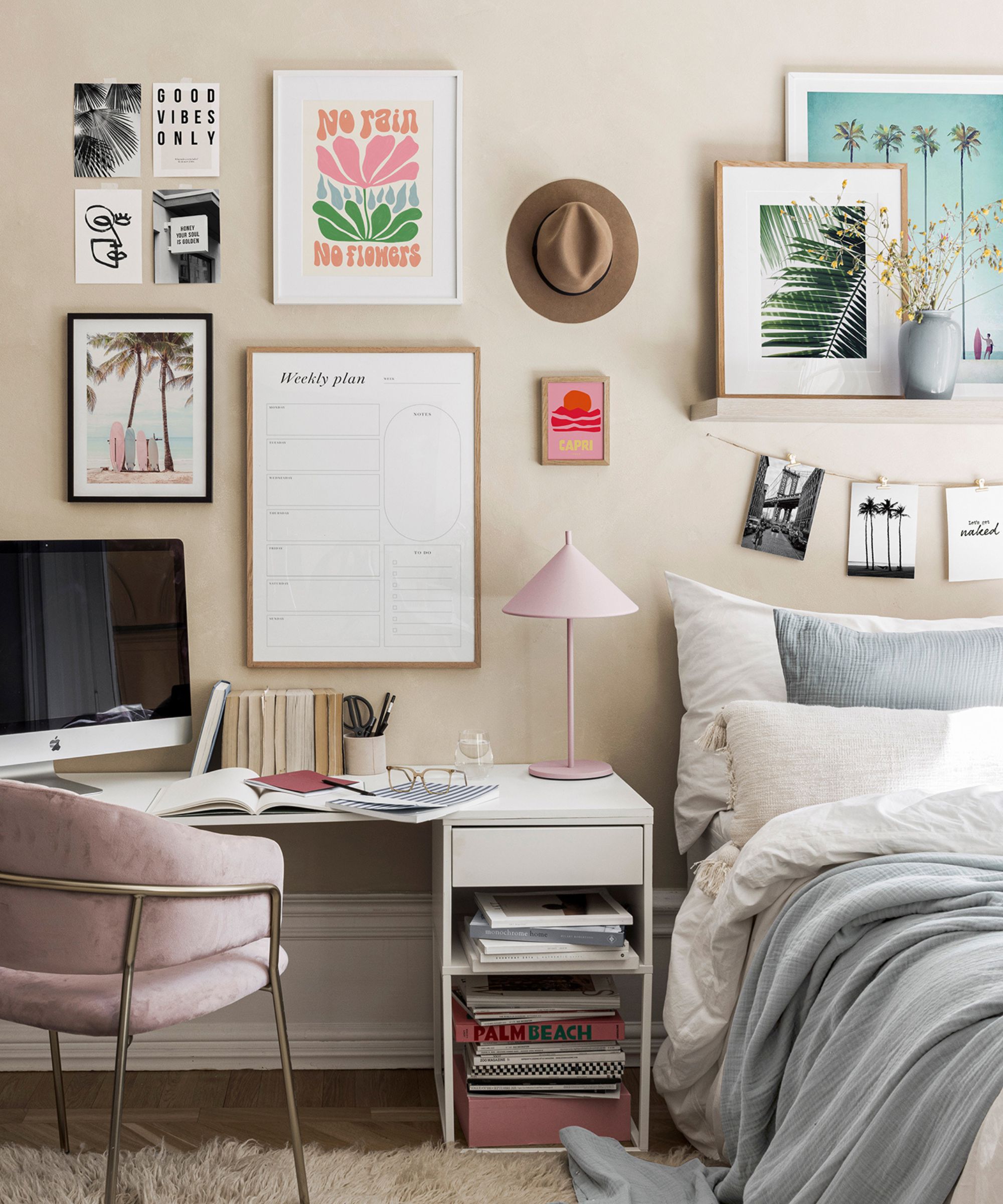 A teenage girls bedroom, with a white desk with a computer monitor and pink desk chair. framed prints and a whiteboard on the wall above.