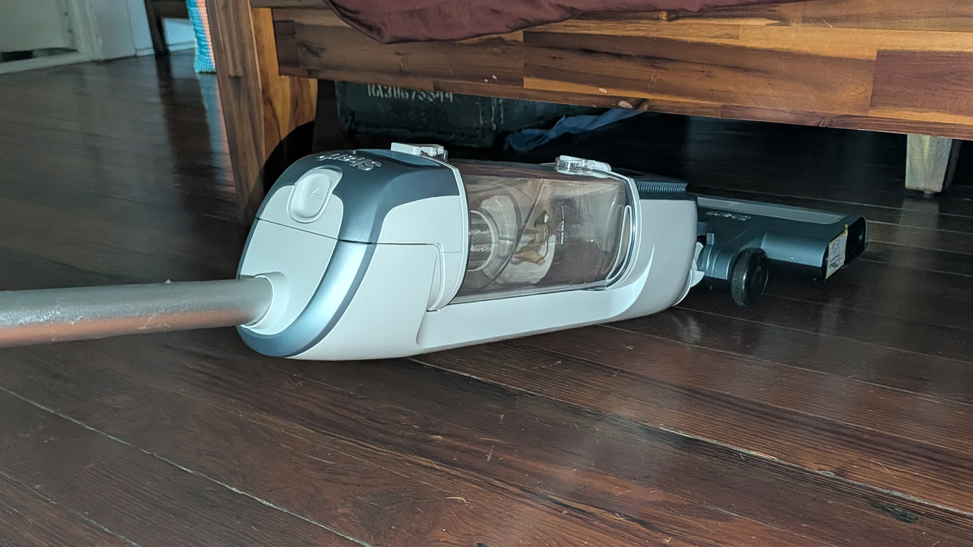 Tester using the Shark Freestyle Max cordless upright vacuum to clean under a cabinet