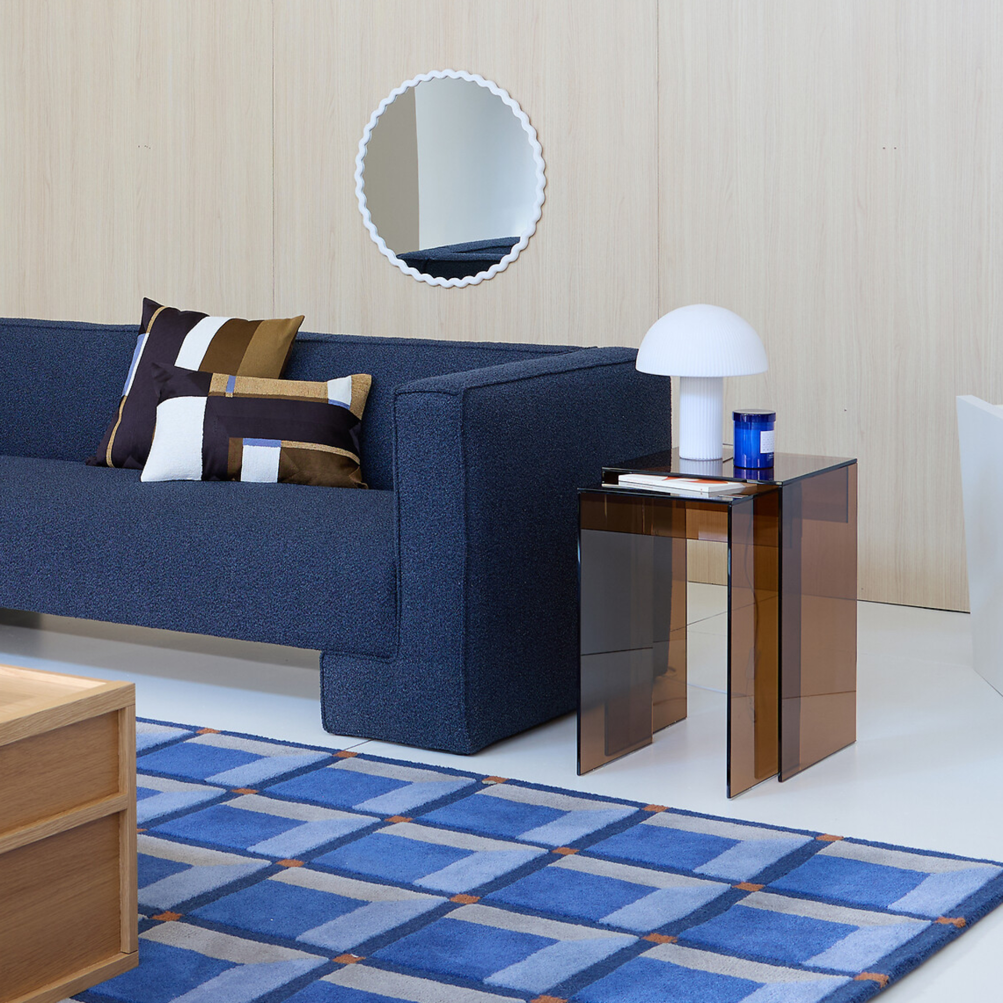 living room with blue sofa, blue rug and brown glass side tables