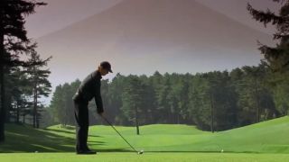 Bill Murray in silhouette lining up a golf swing with Mount Fuji in the background