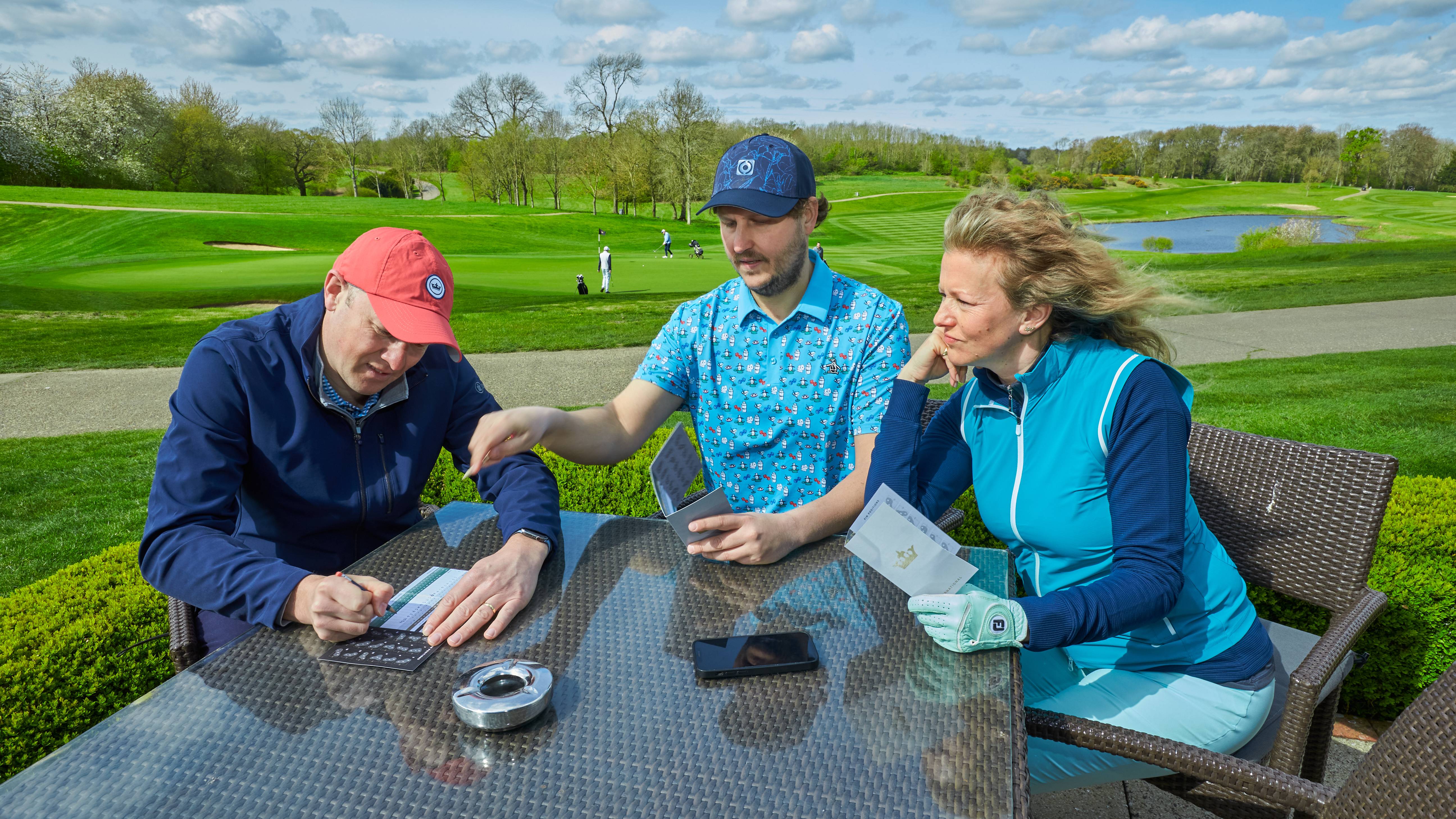 Three golfers marking scorecards