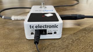 TC Electronic Polytune 3 tuner plugged in on a wooden surface