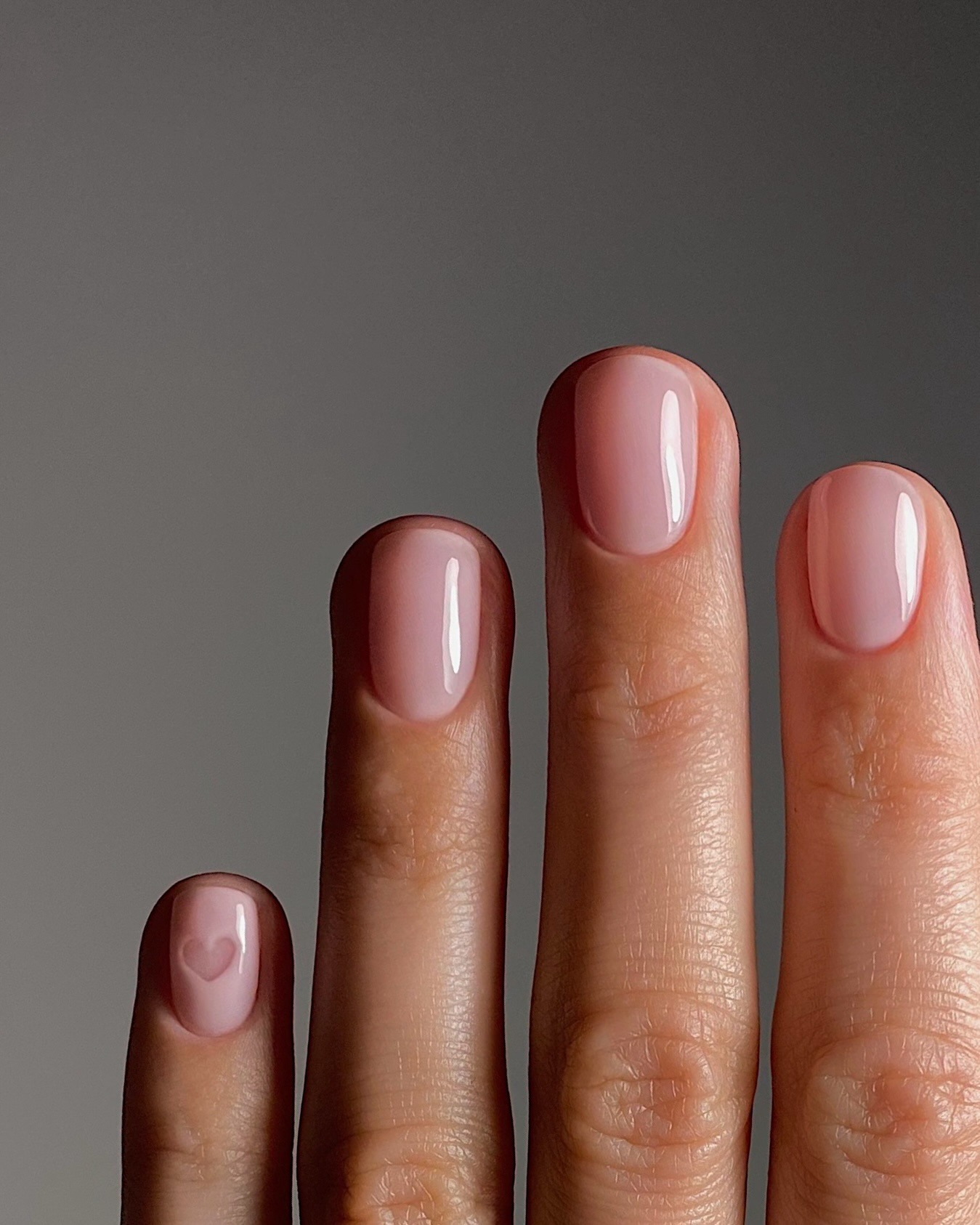 A close-up of a short, milky pink manicure