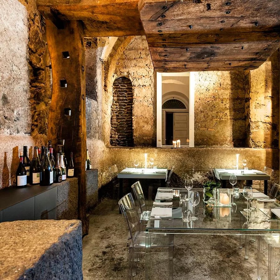 Restaurant in vaulted stone cellar with perspex tables and chairs