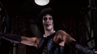 Tim Curry poses in an elevator with a look of delight in The Rocky Horror Picture Show.