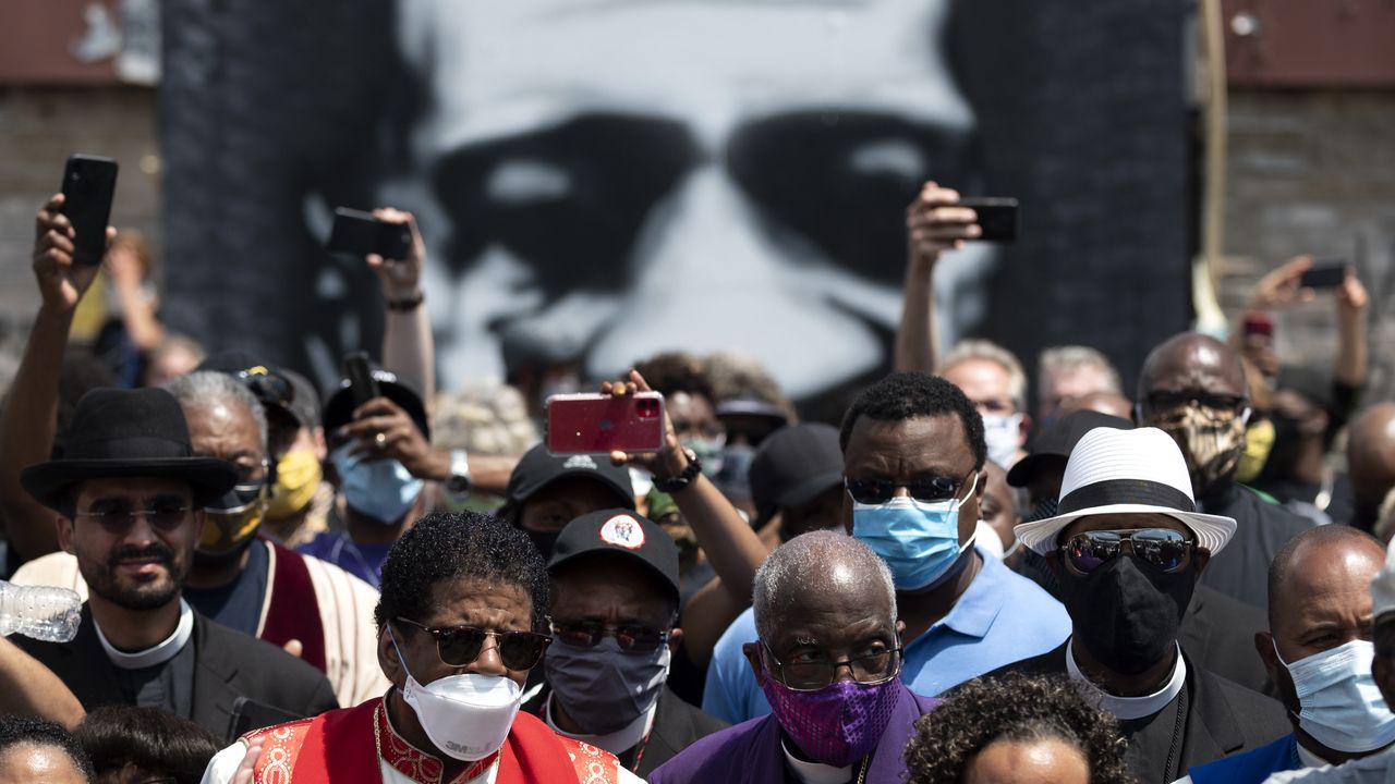 Members of the clergy gather in front of a George Floyd mural in June, 2020