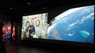 Canadian astronaut David Saint-Jacques speaks live to students in Ottawa, Canada Jan. 22, 2019 from the International Space Station. At right is the view below the orbiting complex.
