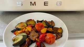 Roasted vegetables on a plate in front of the Smeg 10-in-1 Countertop Oven