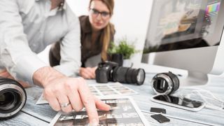 Man and woman at desk looking at printed photos