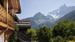 The wooden balcony of a ski chalet over looking a green valley