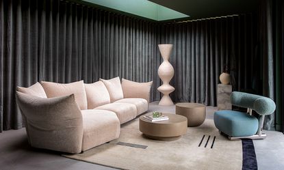 Living space with charcoal curtains, pink sofa and teal armchair