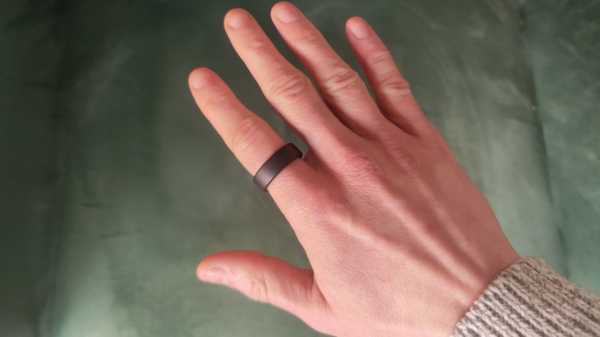 En mörkbrun Oura Ring 3 runt ett finger.