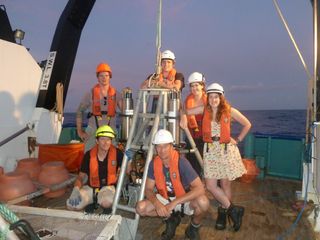 The expedition's scientific team poses with one of the deep-sea landers.