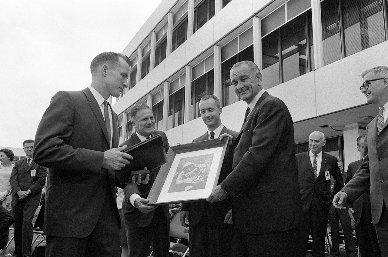 Gemini 4 commander Jim McDivitt (at center) and command pilot Edward White (at left) present President Lyndon B. Johnson with a framed photo of White's historic spacewalk.