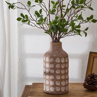 A ceramic vase with imprinted flowers sat on a table
