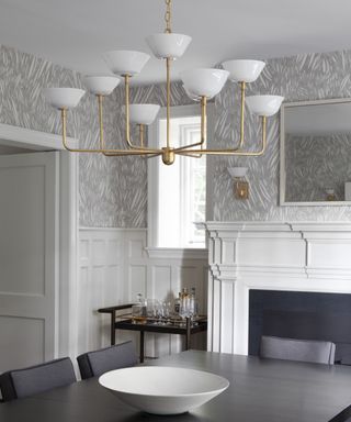 A dining room with a large brass chandelier hanging over the dining table