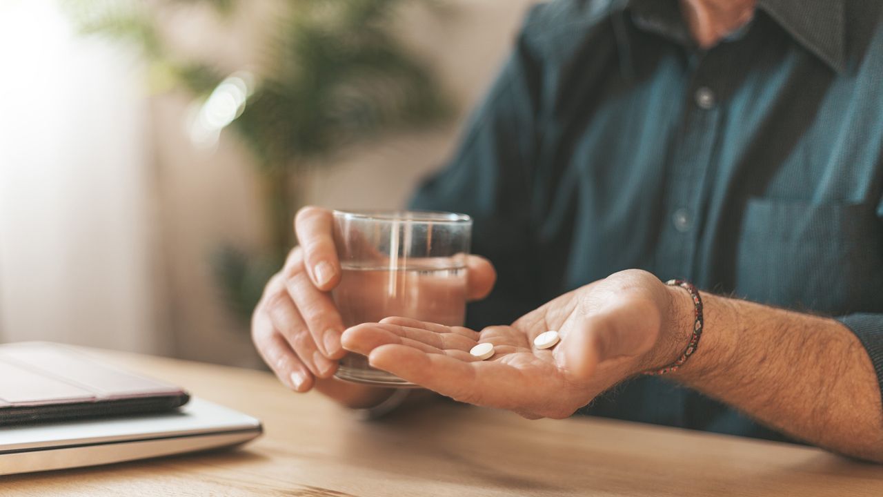 older man taking a supplement at the table