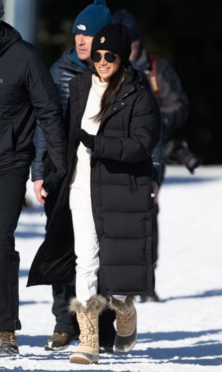 A photo of Meghan Markle sporting a long matte black Aritzia Super Puff at the Invictus Games.