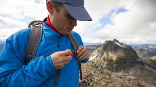 A hiker adjusting the sternum strap on his backpack during a hike