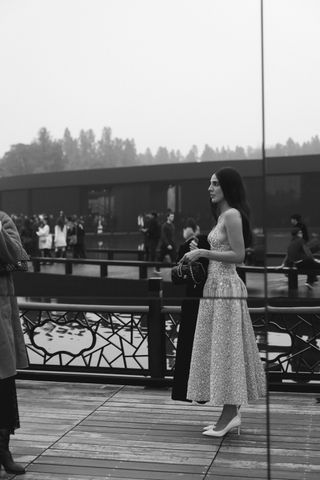 Orion Carloto crosses a bridge wearing a sequin drop waist dress and white pumps