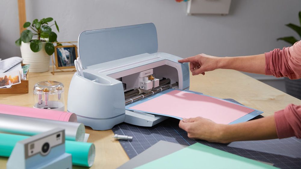 A crafter uses a Cricut Maker 3 bundle on a desk