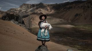 Alina Surquislla Gomez, a third-generation alpaquera (alpaca-farmer), cradles a baby alpaca on the way to her family’s summer pastures, in Oropesa, Peru. The climate crisis is forcing herders, many of whom are women, to search for new pastures, often in difficult terrain.