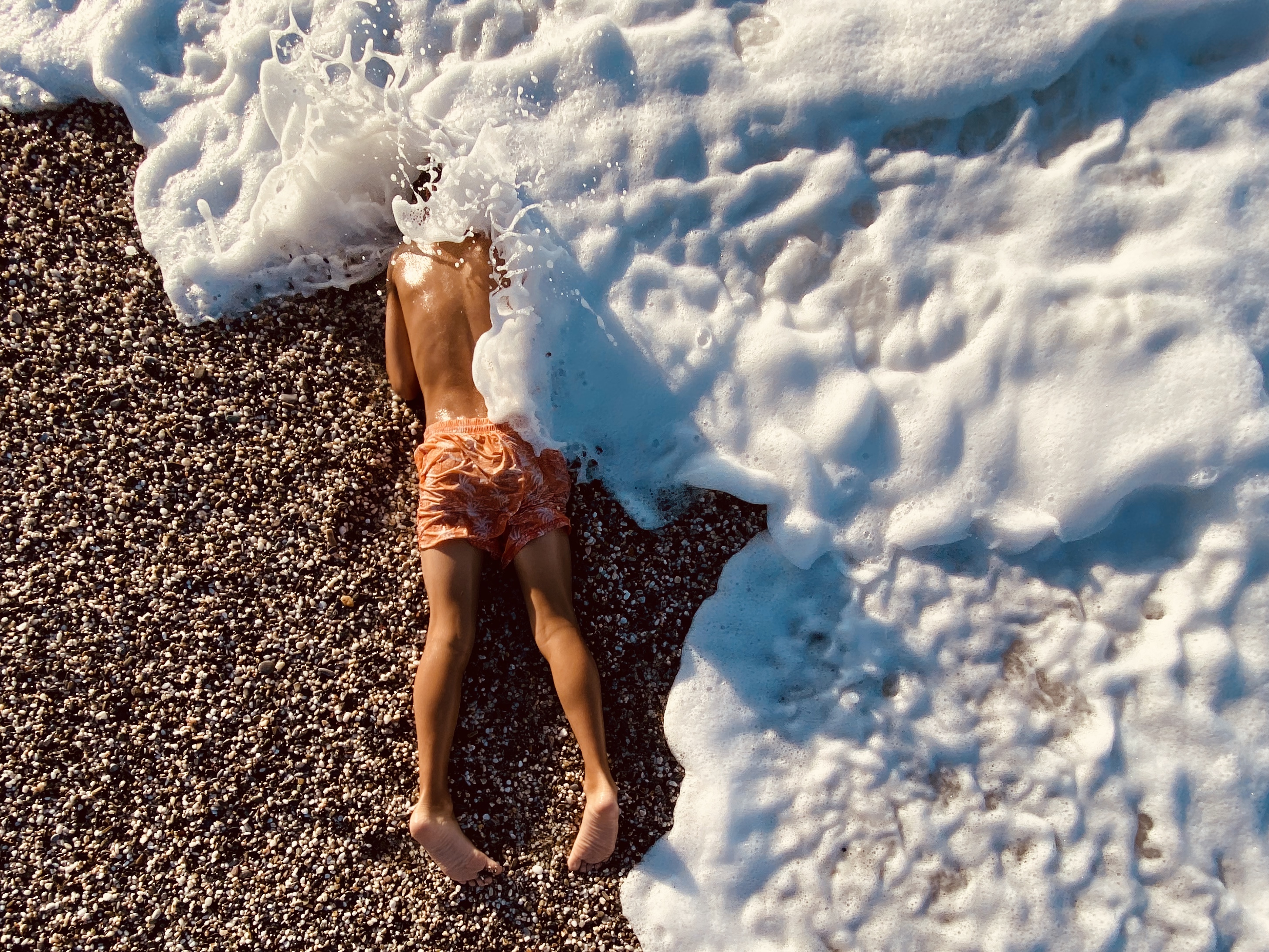 Untitled shot of a child on a beach being hit by a wave for iPhone Photography Awards 2021