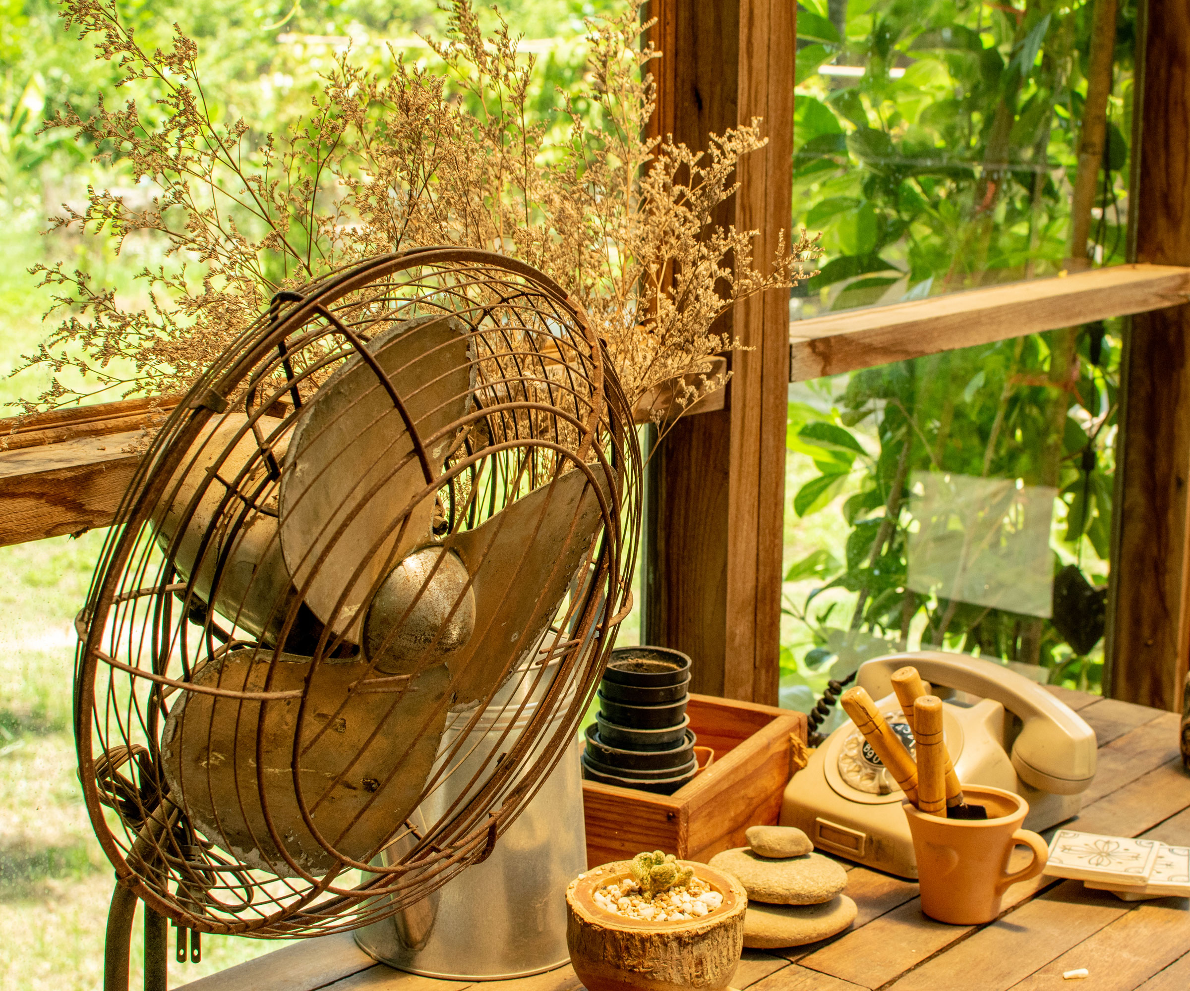 old fashioned desk fan on table near pots, lids and seed marking items