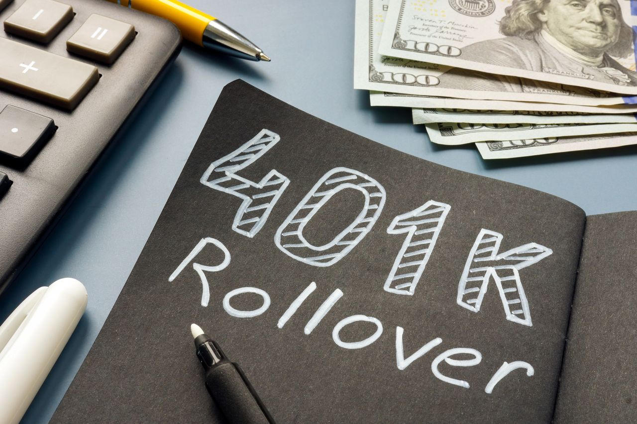 A chalk board with &quot;401k Rollover&quot; lying near cash.