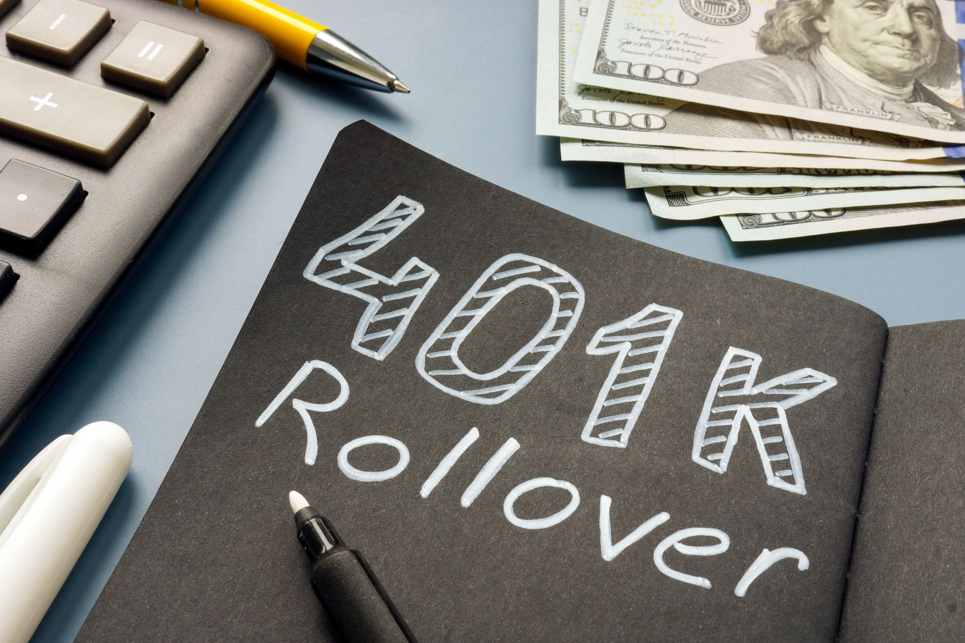 A chalk board with "401k Rollover" lying near cash.