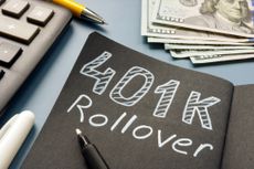 A chalk board with "401k Rollover" lying near cash.