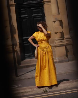 Woman wears a marigold maxi dress.