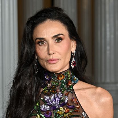 a close up photo of a white woman with long, dark hair posing for paparazzi at a red carpet event