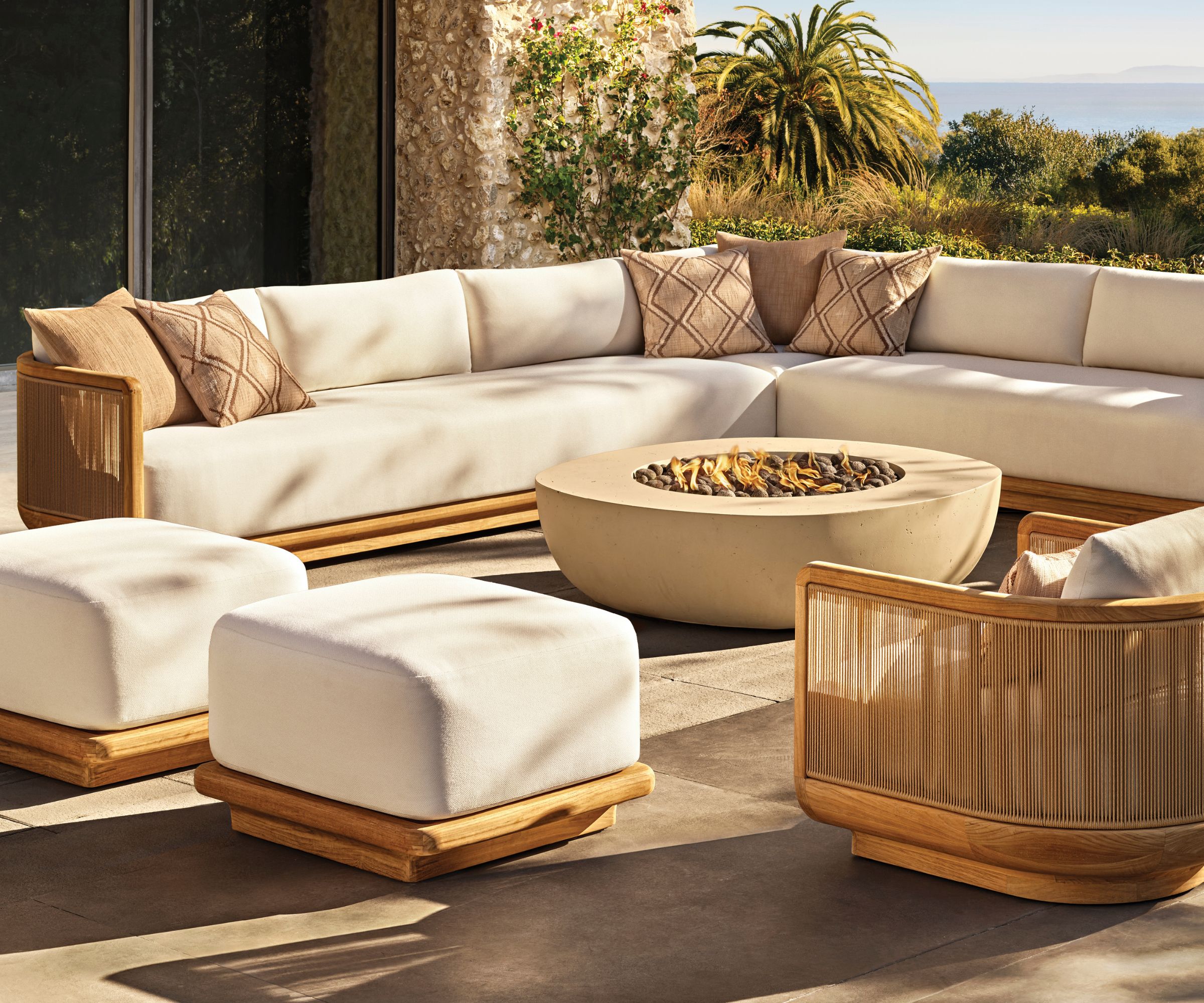 Modular outdoor furniture in light wood and white cushions with a fire pit in the middle