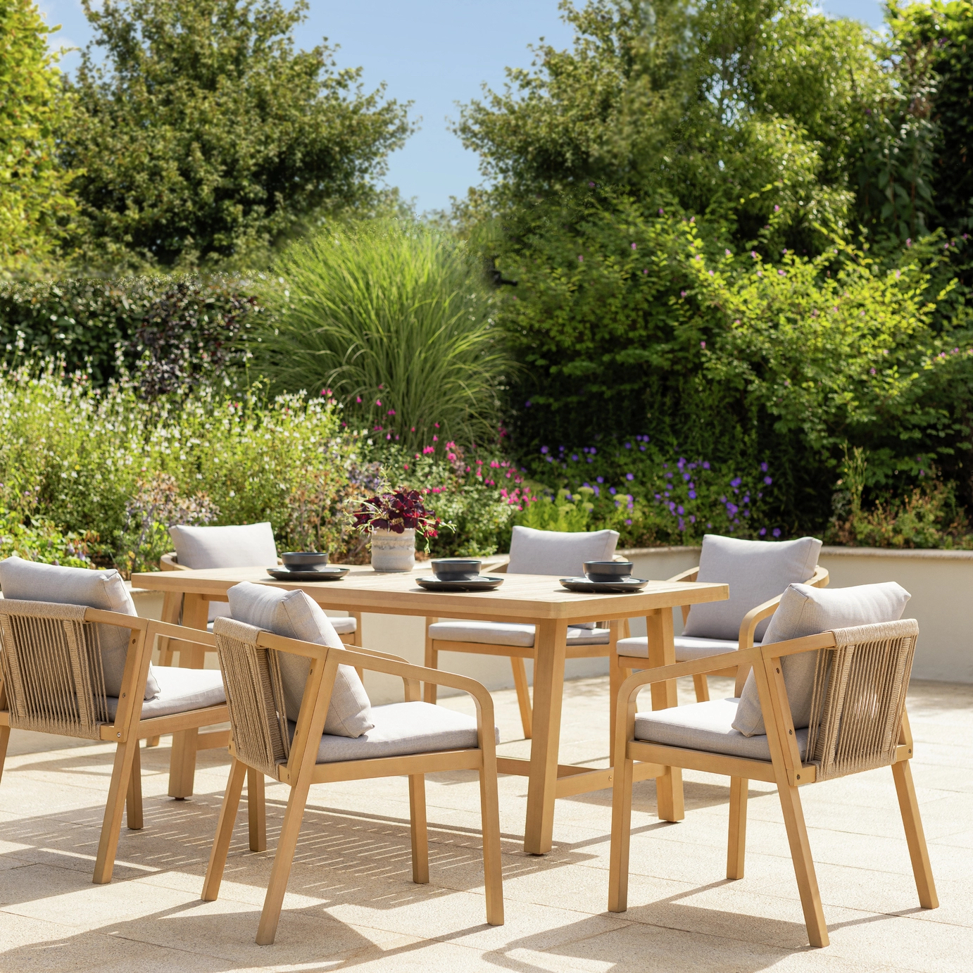 Eucalyptus wood dining table and chair set on patio in garden setting