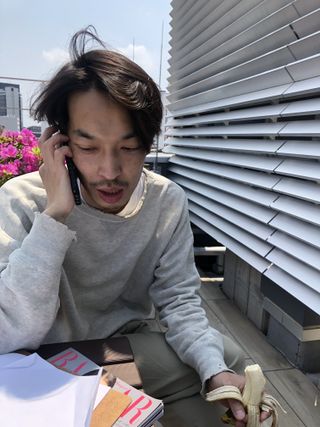 Auralee designer Ryota Iwai on phone eating banana