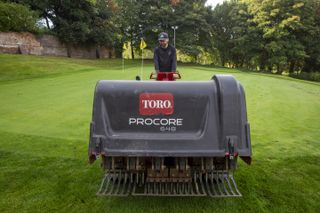 Dan Parker using a procore machine to aerate a green at Edgbaston golf club