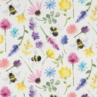 A white fabric square with yellow, purple, and pink flowers and green stems, as well as yellow and black striped bees
